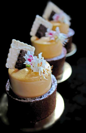 Mango orange spring dessert with chestnut flowers and chocolate napkin decor on black backgroundの写真素材