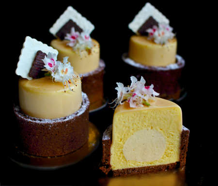 Sliced mango orange spring dessert with chestnut flowers and chocolate napkin decor on black backgroundの写真素材