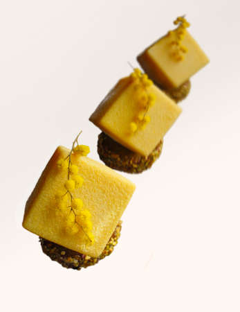 Yellow cube dessert with mimosa flowers on white background top viewの写真素材