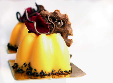 Orange dessert with edible red rose petal and chocolate decorationの写真素材