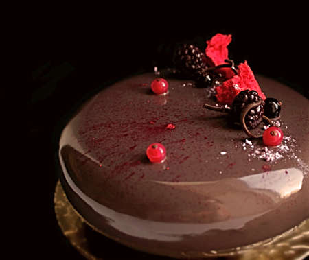 Chocolate cake with shiny mirror glaze, red currants, black currants and blackberriesの写真素材