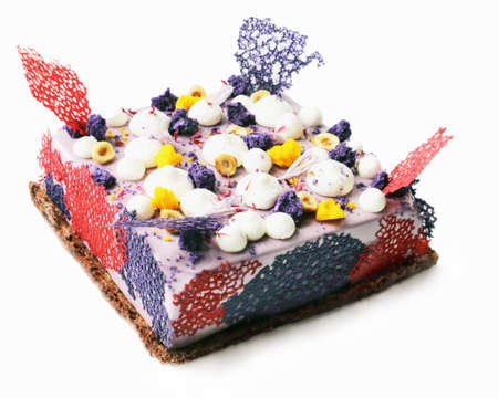 Purple square cake with shiny mirror glaze, cream, nuts and and crepe lace isolated on white backgroundの写真素材