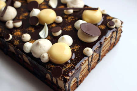 Hazelnut and citrus coffee sheet cake with orange mousse and dark chocolate mirror glaze on whte backgroundの写真素材
