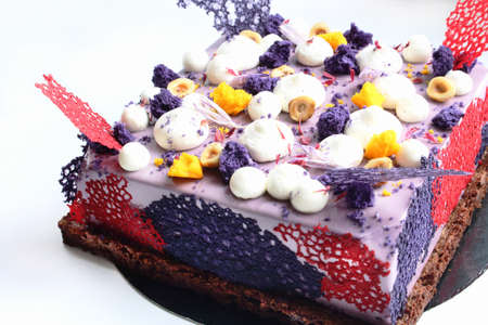 Purple square cake with shiny mirror glaze, cream, nuts and berries on white backgroundの写真素材