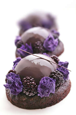 Purple chocolate desserts with shiny mirror glaze, microwave sponge and blackberries on white backgroundの写真素材