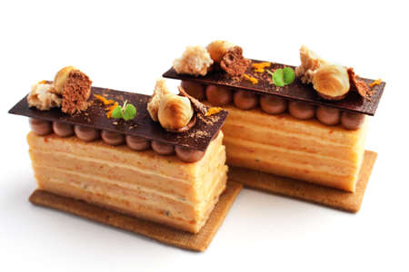 Orange Opera cake slices with hazelnuts, cookie and ganache isolated on white backgroundの写真素材