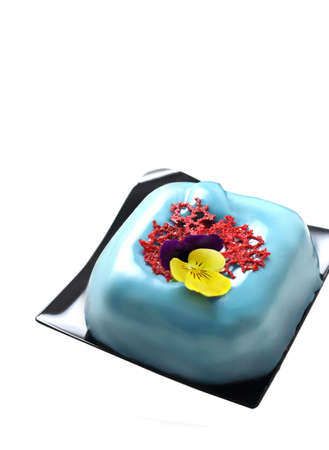 Light blue square dessert with red coral lace crepe and edible flower isolated on white backgroundの写真素材