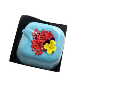 Light blue square dessert with red coral lace crape and edible flower isolated on white backgroundの写真素材