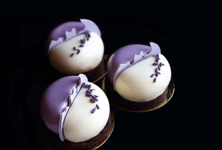 Purple and white round mousse lavender desserts with lavender petals on black backgroundの写真素材