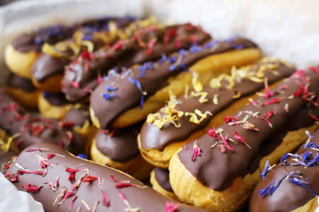Spring eclairs with chocolate glaze and knapweed flower petals in boxの写真素材