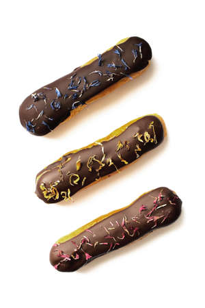 Spring eclairs with chocolate glaze and knapweed flower petals on white background, top viewの写真素材