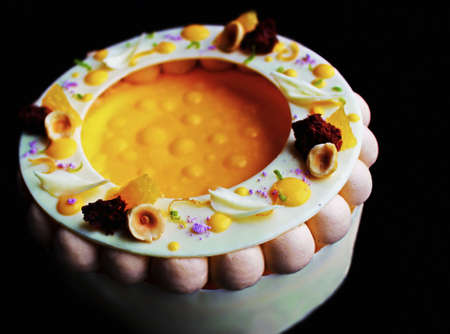 Colorful fancy orange and hazelnut cheesecake isolated on black backgroundの写真素材