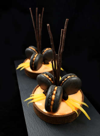 Orange chocolate tarts with black french macarons and persimmonの写真素材