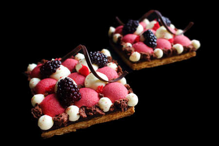 Red currant mousse and blackberry puff pastry desserts with whipped ganache and chocolate spiral decorationの写真素材