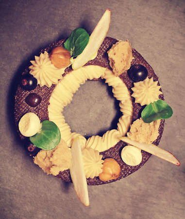 Rustic Paris Brest choux pastry ring with hazelnut ganache, nuts, apple slices, black currants and hazelnut spongeの写真素材