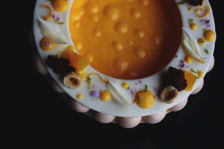 Colorful fancy orange and hazelnut cheesecake isolated on black backgroundの写真素材