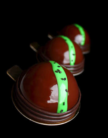 Avocado and chocolate desserts with mirror glaze and black sesame seeds on black backgoundの写真素材