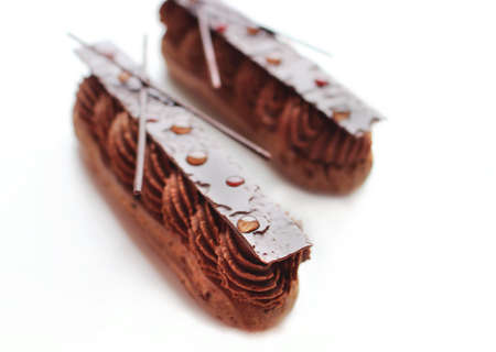 Two chocolate ganache eclairs with shiny chocolate decorationsの写真素材