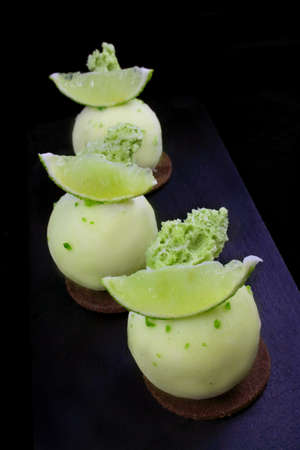 Green lime desserts on chocolate cookie with fresh lime slices and lime zestの写真素材