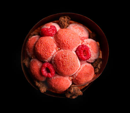 Big red raspberry dessert with fresh raspberries and textured chocolate glaze close up on black background top down viewの写真素材