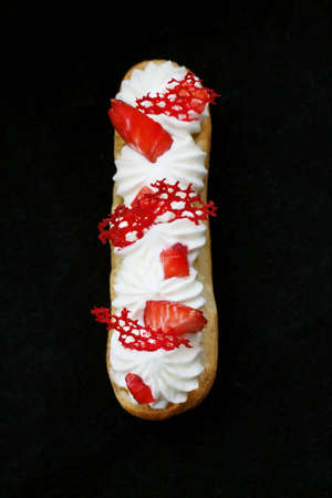 Strawberries and cream eclair with fresh berries and red lace tuile top down on black backgroundの写真素材