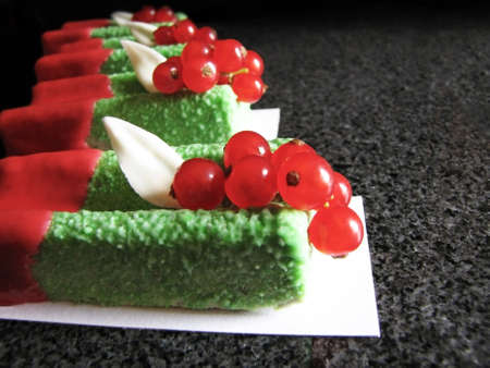 Green basil mousse desserts with red currants and red glaze on marble table