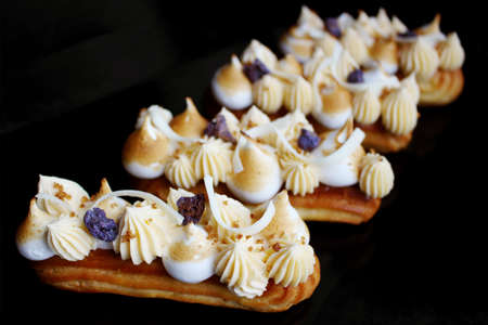 Lemon pie eclairs with purple crumble, citrus ganache and meringue side viewの写真素材