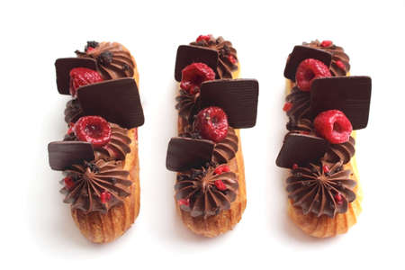 Chocolate and raspberry eclairs with chocolate decorations and fresh berriesの写真素材