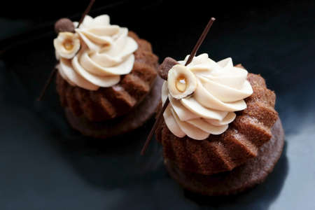 Chocolate modern cupcakes with hazelnuts whipped ganache frosting on black backgroundの写真素材