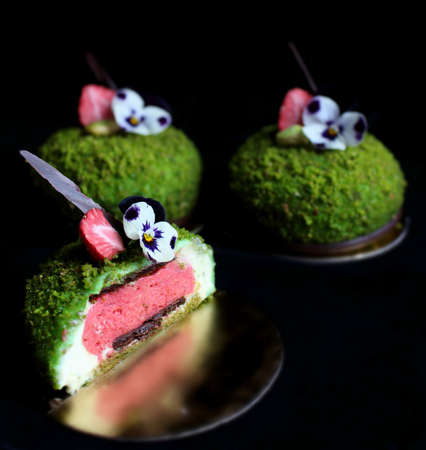 Sliced green textured pistachio dessert with edible pansy flowers and dried strawberriesの写真素材