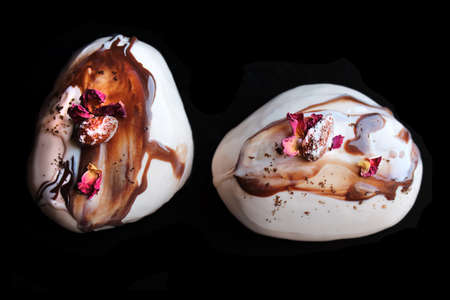 Caramel, coffee and chocolate stone desserts with almonds and rose petals top down on black backgroundの写真素材