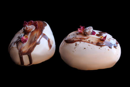 Caramel, coffee and chocolate stone desserts with almonds and rose petals on black backgroundの写真素材