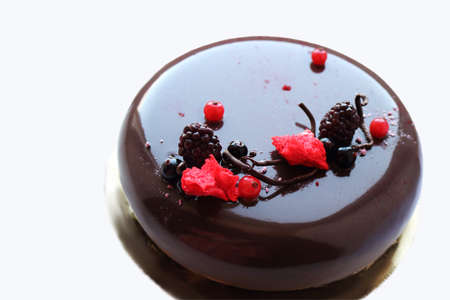 Dark glazed chocolate cake with berries on white backgroundの写真素材