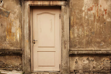Old aged white door in weathered dirty concrete wallの写真素材