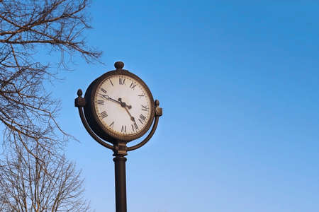 Outdoor clock with roman numerals on spring blue sky backgroundの写真素材