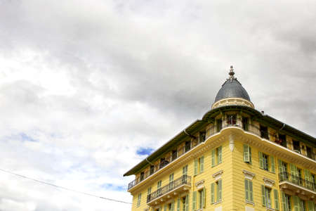 Yellow fancy building corner with dome on cloudy sky backgroundの写真素材