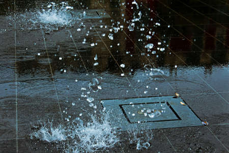 Atmospheric falling fountain water drops splashes on smooth shiny dark ceramic tiles