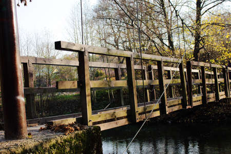 Long old wooden bridge over a river in autumn park