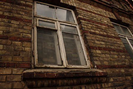 Big dirty window in old dark brick wall with dirty glass