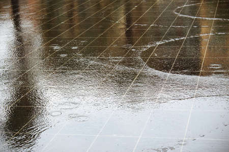 Square street fountain water puddle with ripples and street sign reflection