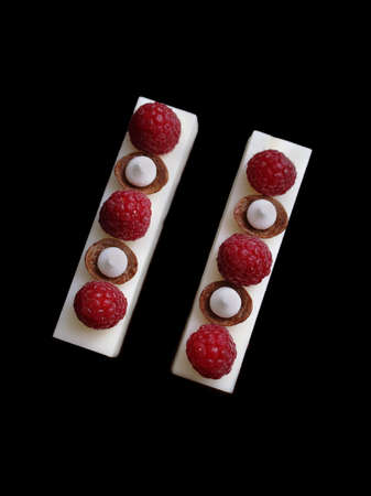 White mousse desserts with raspberries and meringues on brownie base flat lay isolated on black backgroundの写真素材