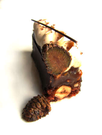 Caramel and hazelnut cake piece with cut candied pinecone on white background