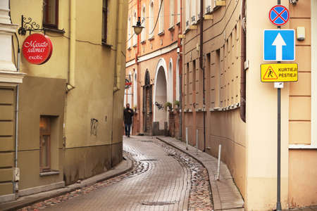 Curvy Old town street with cafe and street signs in Vilniusのeditorial素材