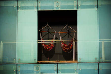 Two red hammocks hanging on modern building balcony
