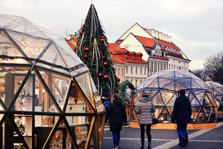 City square christmas fair with people walking between glass shops around a christmas tree