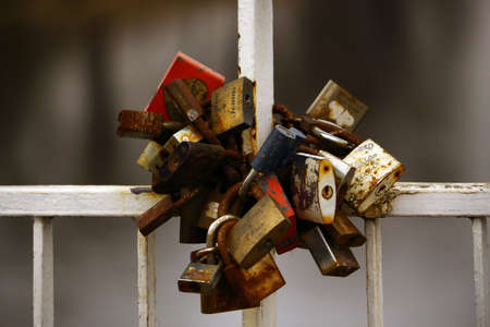 A bunch of old rusty wedding day padlocks hanging on bridge handrailの写真素材