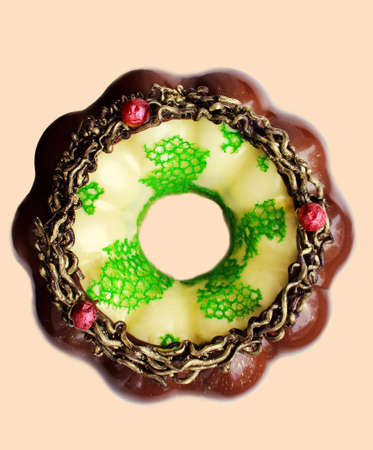 Christmas cream and chocolate wreath cake with cranberries, mirror glaze and green coral lace on beige background top viewの写真素材
