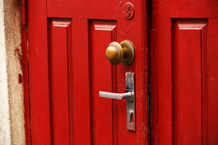 Red wooden door with round ornate handle and traditional handle slightly openの写真素材