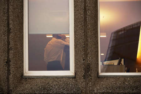 White window in soviet union concrete building with working businessman talking on the phone in the...