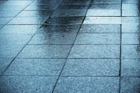 Blue wet tiled shiny square pavement with reflectionsの写真素材